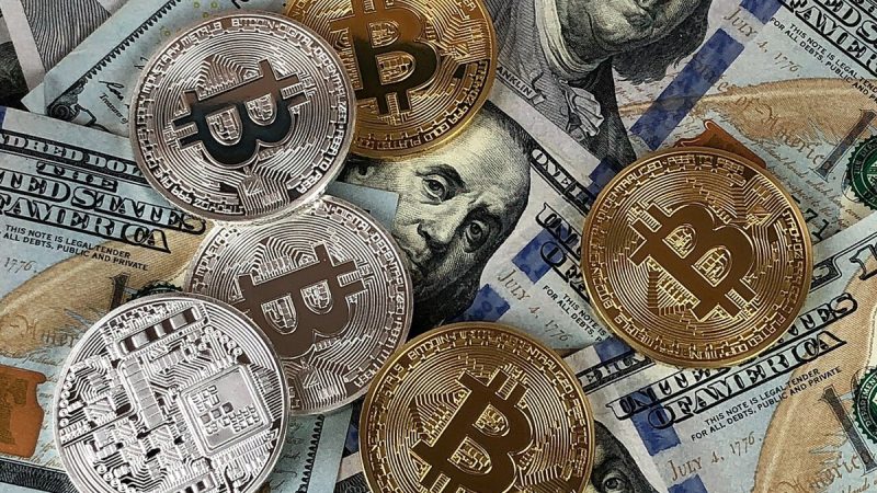 Physical bitcoin coins resting on United States dollar banknotes