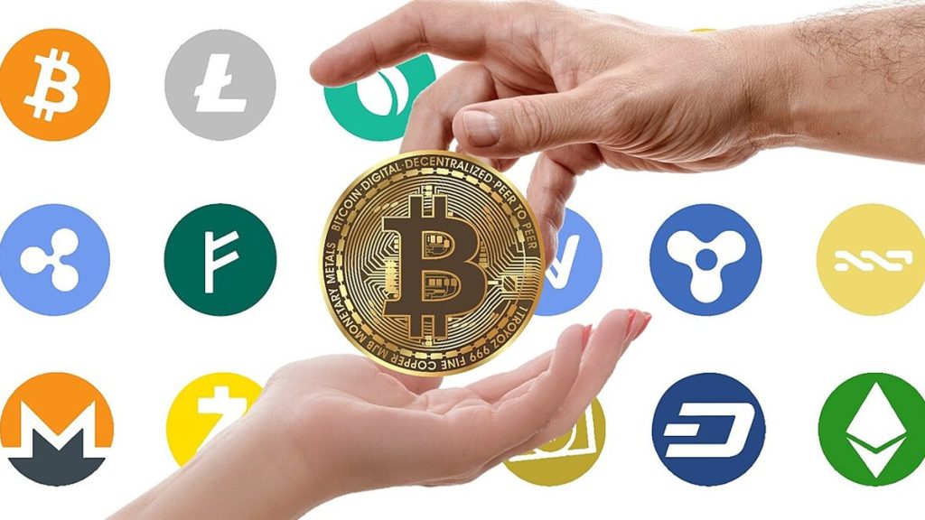 Hands passing a gold bitcoin coin surrounded by cryptocurrency logos
