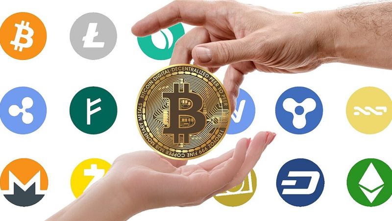 Hands passing a gold bitcoin coin surrounded by cryptocurrency logos